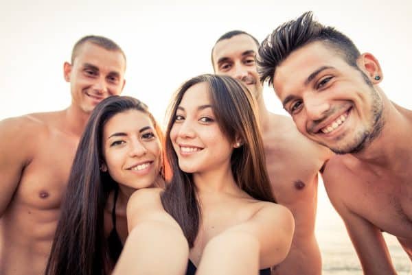 Swinging: Swinger gruppe har det kjekt på stranden. Tre menn og to damer.