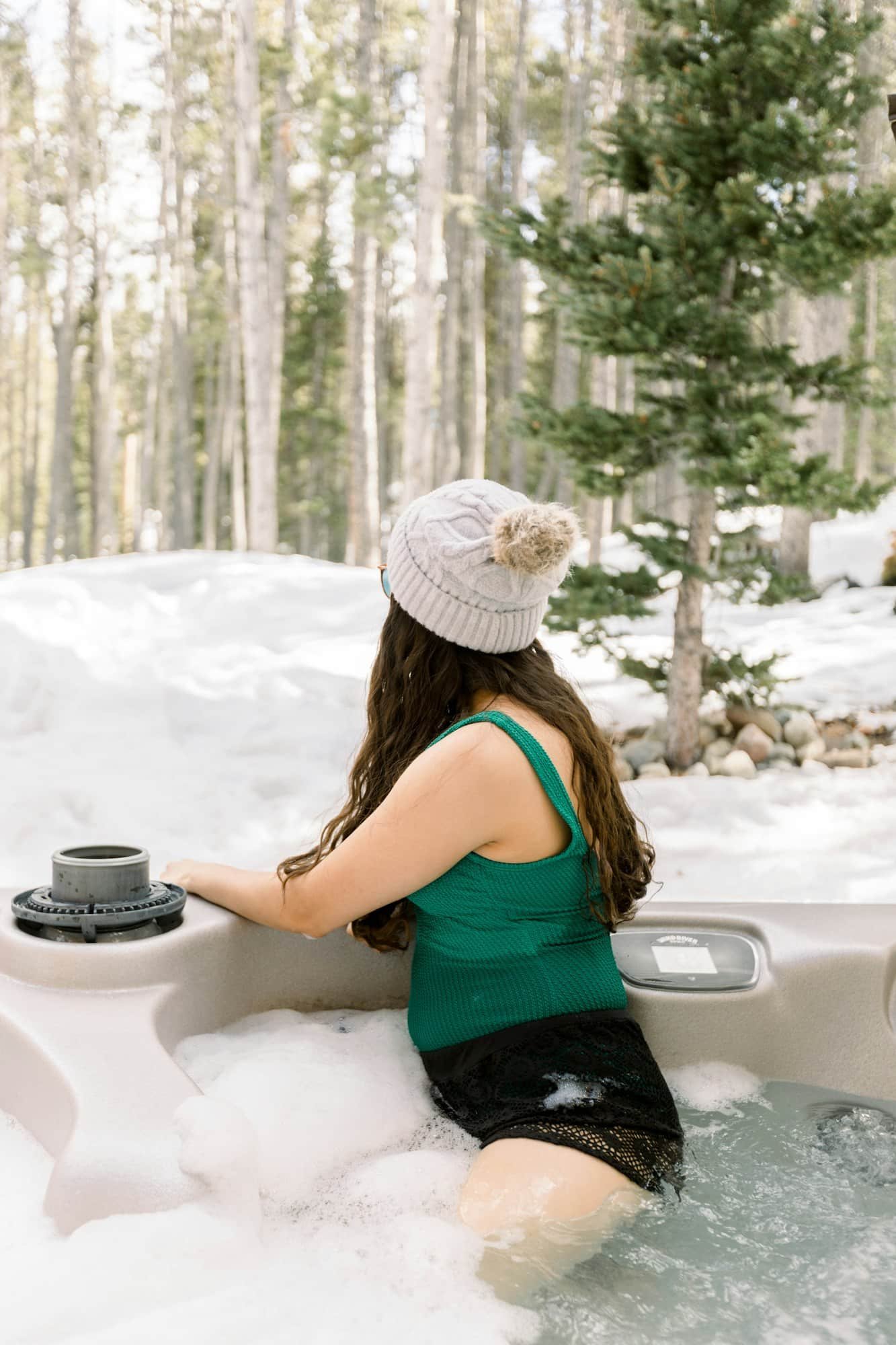 Woman enjoying the day in a hot tub outside a cabin during winter