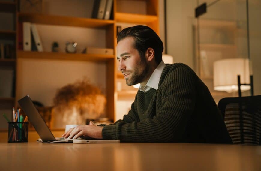 Flott mann sitter i et halvmørkt rom med en laptop. Ilustrerer den erotiske novellen "fersket" som handler om en mann som blir fersket av sin kone når han sitter og onanerer foran PC-skjermen.